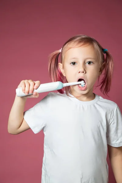 Sonriente niña caucásica limpiando sus dientes con un cepillo de dientes sónico eléctrico — Foto de Stock