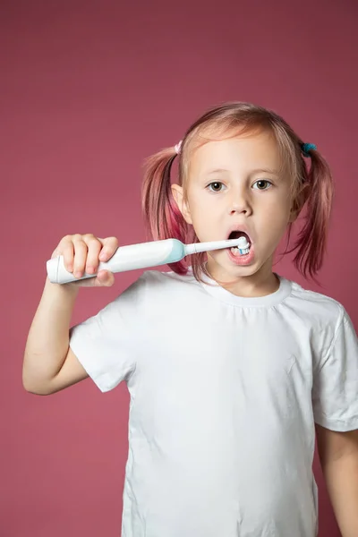 Leende kaukasiska lilla flicka städa tänderna med elektrisk sonic tandborste Royaltyfria Stockfoton