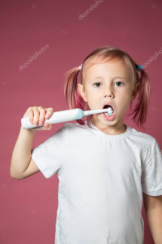 Smiling caucasian little girl cleaning his teeth with electric sonic toothbrush 