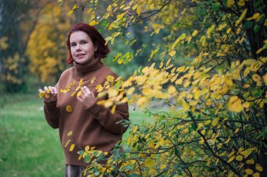 Sonbaharda sarı orman ağaçlarına karşı yetişkin bir kadının portresi.
