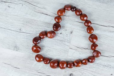 Tahta bir arka planda kalp şeklinde kestaneler.