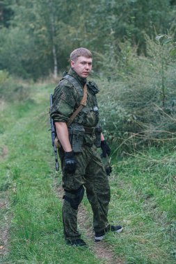 Tam teçhizatlı askeri adamlar otomatik silahlarla hava yumuşak top oynamaya hazırlanıyorlar.