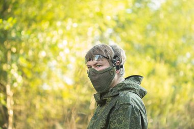 Tam teçhizatlı, güvenlik maskeli ve otomatik silahlı askerlerin portresi hava yumuşak top oynamaya hazırlanıyor.