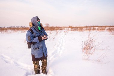 Mavi ceketli beyaz adam uzaktan kumandayla uçan bir dron fırlatıyor.