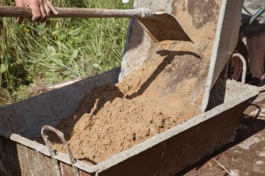 Bahçe yolu açmak için çimento karışımına kum yüklemek, bahçe arazisi inşaatı.