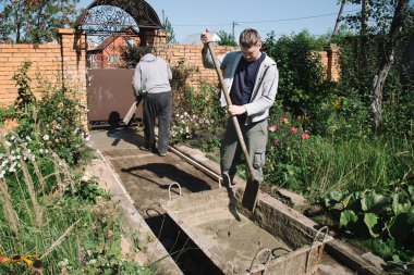 30 yaşında bir adam çimento karışımını büyük bir konteynırda karıştırıyor.
