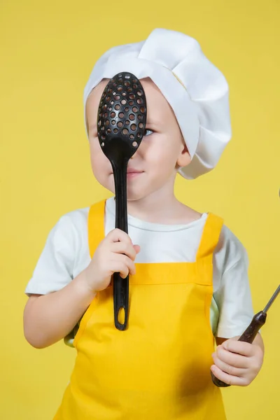 扮演厨师的小高加索男孩 穿着围裙的男孩和戴着黄底厨师帽的男孩 — 图库照片