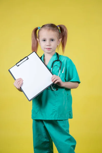 穿着医生绿色外套 手里拿着一块用黄色隔开的石碑的严肃的高加索小女孩的画像 — 图库照片