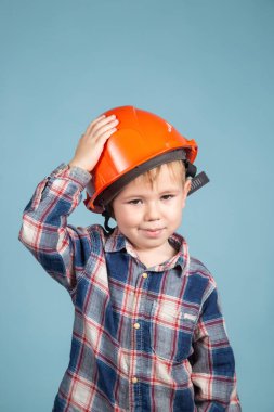 Mavi arka planda turuncu kasklı şirin bir çocuğun portresi..