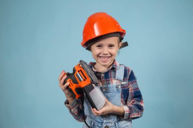 Güzel beyaz kız elinde elektrikli zımpara makinesiyle inşaat kaskı takıyor.
