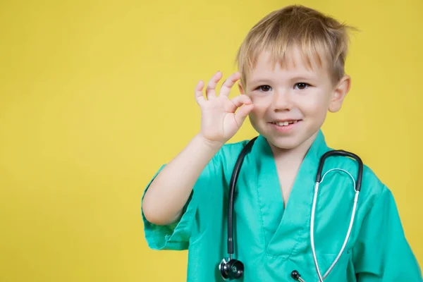 Porträt Des Niedlichen Kleinen Kaukasischen Jungen Ärzte Grün Gekleidet Zeigt lizenzfreie Stockbilder