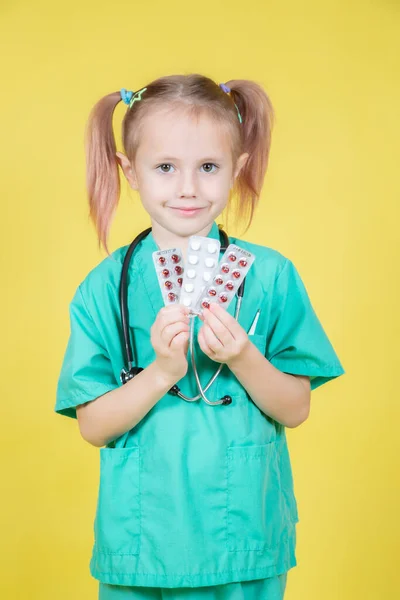 Portrait of little girl dressed in doctors coat holds blisters with pills — Fotografia de Stock