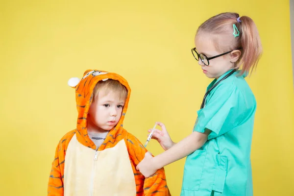 小孩扮演医生 一个打扮成医生的女孩给一个打扮成老虎的男孩打针 — 图库照片