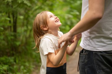 Baba ve kızı yazın ormanda yürür, kız babasının elini tutar ve gözlerinin içine bakar.