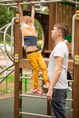 Babası ve küçük beyaz kızı yazın oyun bahçesinde oynuyorlar.