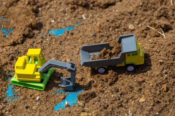 沙盒中鲜艳的黄色绿色塑料玩具卡车 — 图库照片