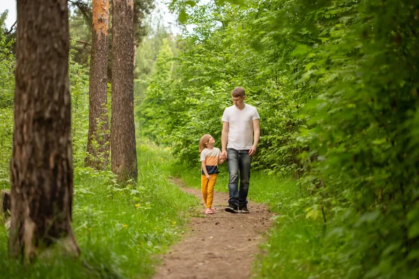 Pai e filha caminham na floresta no verão, a menina segura a mão dos pais — Fotografia de Stock