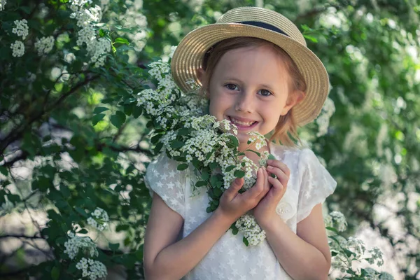 美しいですCaucasian女の子の肖像画でBohoドレスで開花ブッシュで選択的な焦点とソフトフォーカスを持つスパイアの白い花 — ストック写真