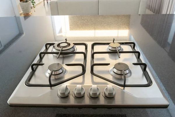 Modern hob gas stove made of stainless steel using natural gas or propane for cooking products on black countertop. Stove top cooking. The upper part of gas cooking range.