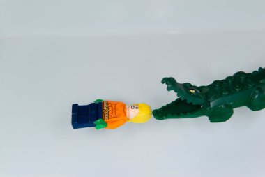 Bauru, Brezilya. 7 Haziran 2022: Aquaman 'in küçük lego figürünün beyaz arka plandaki havuzunda kızgın bir timsahla yüzen göbeğinin en üst görüntüsü. Uzay alanı. Minyatür figür Lego Grubu tarafından yapılır