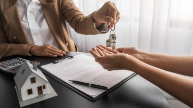 Emlakçının elinde anahtar var ve müşteriden satın almak, sigorta yaptırmak ya da emlak veya emlak almak için sözleşme istiyor..