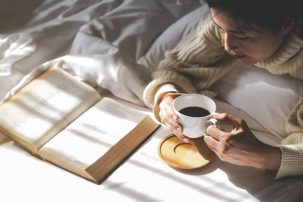 Ázsiai Kezében Egy Csésze Kávét Olvasni Egy Könyvet Ágyon Után — Stock Fotó
