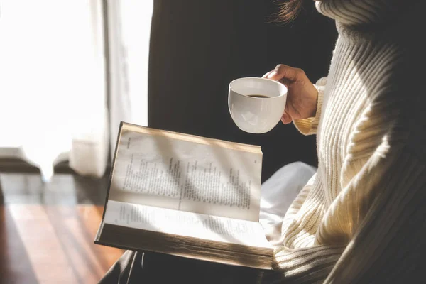 Ázsiai Kezében Egy Csésze Kávét Olvasni Egy Könyvet Ablak Mellett — Stock Fotó