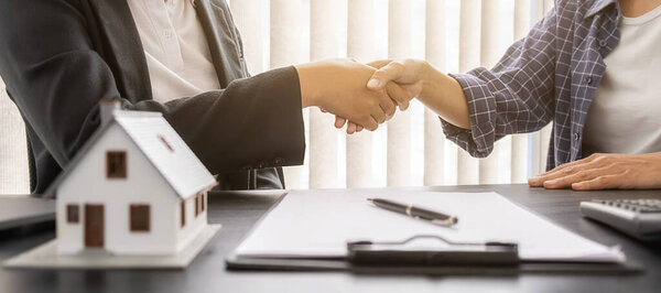 Модель дома с агентом и клиентом обсуждается для контракта на покупку, получить страхование или кредит недвижимости или собственности.