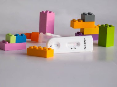 SARS-CoV-2 Antijen Hızlı Testi (nazal Swab), beyaz üzerine kenetlenmiş oyuncak tuğlaları arasında negatif sonuç veren bir çubuk ve test kaseti ile kendini test etmek için. COVID-19 Ag. Çocukluktaki salgın kavramı