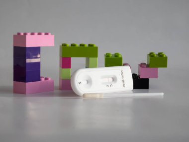 SARS-CoV-2 Antijen Hızlı Testi (nazal Swab), beyaz üzerine kenetlenmiş oyuncak tuğlaları arasında negatif sonuç veren bir çubuk ve test kaseti ile kendini test etmek için. COVID-19 Ag. Çocukluktaki salgın kavramı