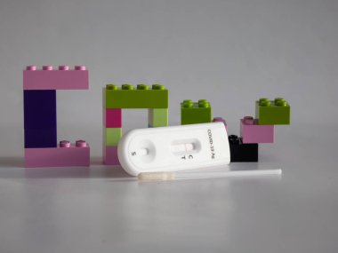 SARS-CoV-2 Antijen Hızlı Testi (nazal Swab), beyaz üzerine kenetlenmiş oyuncak tuğlaları arasında negatif sonuç veren bir çubuk ve test kaseti ile kendini test etmek için. COVID-19 Ag. Çocukluktaki salgın kavramı