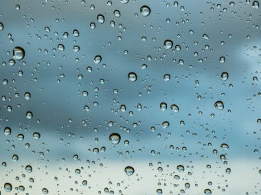 Büyük, yuvarlak su damlacıklarıyla dolu bir makro çekim yağmurdan sonra arka planda dramatik, kara bulutlar