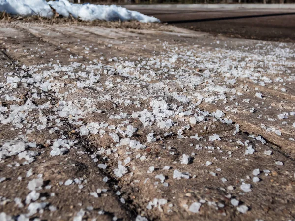 Kışın güneş ışığında buz gibi kaldırım yüzeyinde büyük, beyaz tuz taneleri. Yüzeyi açık tutmak ve insanları kış mevsiminde buzdan ve kardan korumak için yollara tuz uygulamak