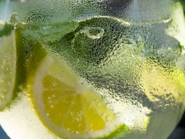Yeşil nane yapraklı Makro boy mojito, beyaz rom, limon, limon, soda ve buz. Güzel makro mojito kokteyl bardağı güneş ışığıyla kaplı.