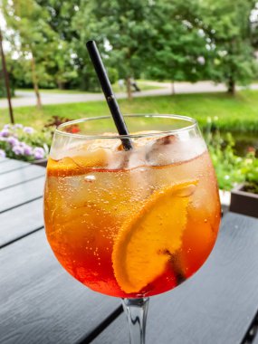 Prosecco, aperol, soda, portakal dilimleri ve buzlu Aperol kokteyli. Açık hava restoranında yoğunlaştırılmış turuncu kokteyl bardağının güzel makro görüntüsü.