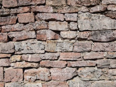 View of empty, old white, pink and grey brick wall background with copy space. A deteriorating old brick wall outdoors in bright sunlight