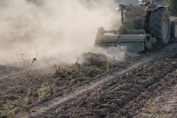 Genç çiftçi, toza bulanmış traktöründeki yeni ürün için toprağı hazırlıyor.