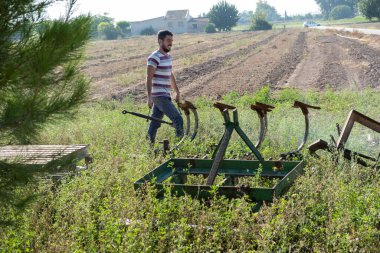 Genç çiftçi meyve bahçesinin ekimine başlamak için çiftlik aletlerini hazırlıyor..