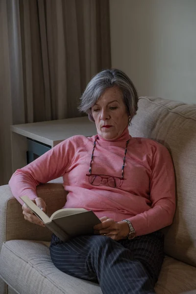 Konsept hobi. Evdeki kanepede kitap okuyan son sınıf öğrencisi bir kadın.