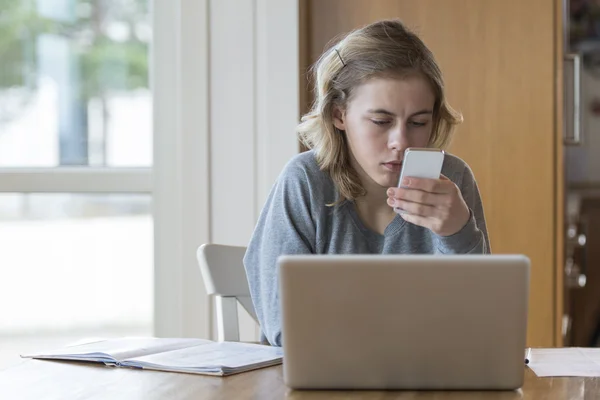 Chica joven trabajando en un ordenador portátil y un teléfono Fotos de stock libres de derechos