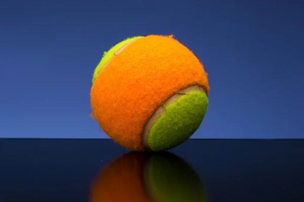 Pelota de tenis para niños con raqueta de tenis sobre fondo azul — Foto de Stock
