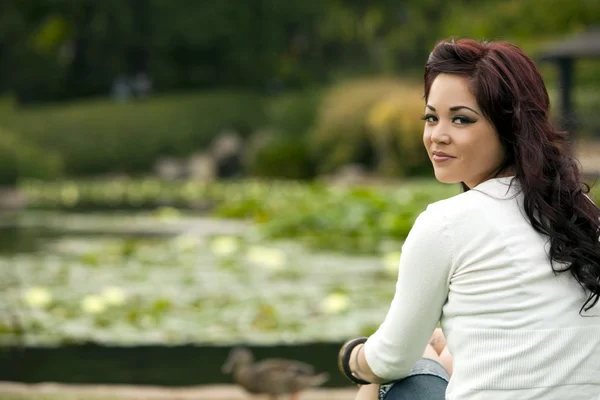 Mujer étnica sentada junto a un lago sereno — Foto de Stock