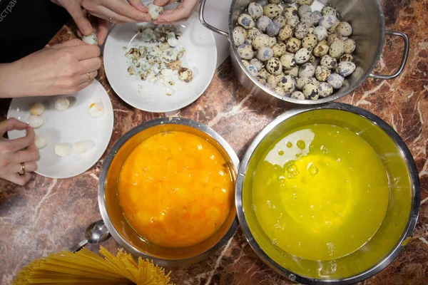 Flat lay of cracked raw quail eggs. Top view. Quail protein and yolk, noone. Hands peeling eggs. Cooking, baking, pasta sause. Food photography.