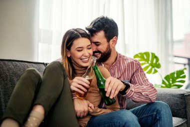 Genç çift evde eğleniyor, bira içiyor ve televizyon seyrediyor. Kadın ve erkeğin kapalı alanda çekilmiş bir portresi televizyon izliyor..