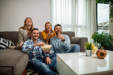 Neşeli bir arkadaş grubu televizyonda futbol maçı izliyor. Arkadaşlık, insanlar ve yaşam tarzı konsepti.