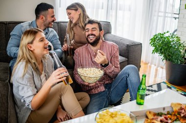 Neşeli bir arkadaş grubu televizyonda futbol maçı izliyor. Arkadaşlık, insanlar ve yaşam tarzı konsepti.