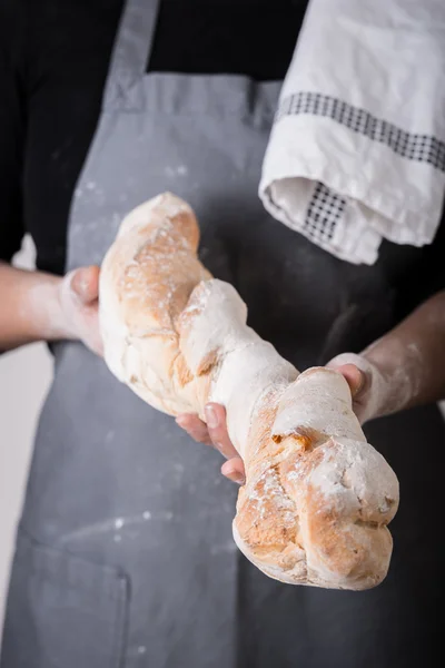 Пекарь представляет свежий хлеб или багет — стоковое фото