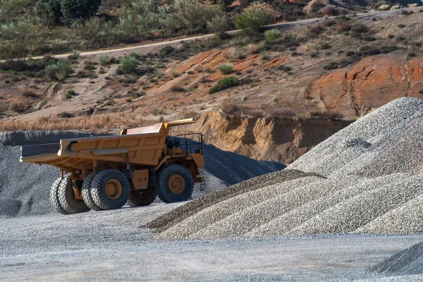 採石場で砂利の山を通って運転する巨大なダンプトラック — ストック写真