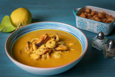 Karides, midye, istiridye, hake ve kalamar bazlı deniz ürünleri çorbası kızarmış ekmek ve limonla servis edilir..