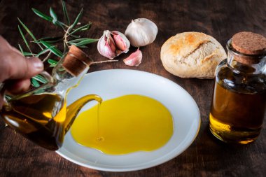 Yağlı bir adamın eli ekmeğin içine ekstra saf zeytinyağı döküyor..